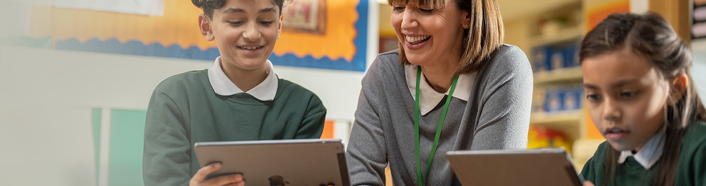 Teacher with kids in front of iPads having a fun time while learning in classroom 