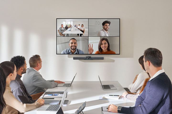 Personen in einem Besprechungsraum, die auf den Bildschirm mit einer Videoleiste blicken