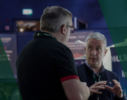 Two people engaged in conversation at a technology expo focusing on exchange and innovation
