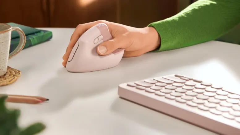 Hand operating ergonomic vertical mouse next to keyboard on bright desk in work environment