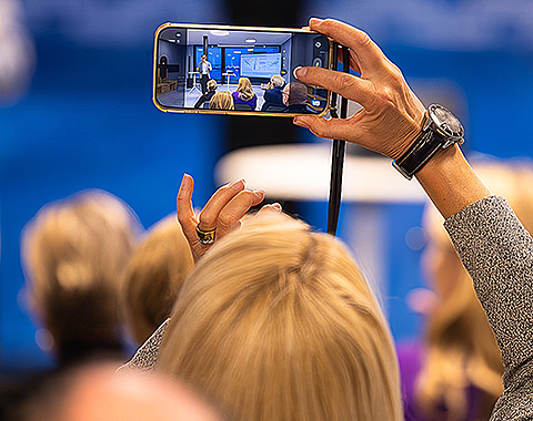 Ein Teilnehmer der Veranstaltung filmt die Präsentation mit seinem Handy.