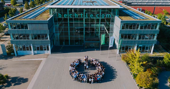 Große Gruppe von Mitarbeitenden vor modernem Bürogebäude