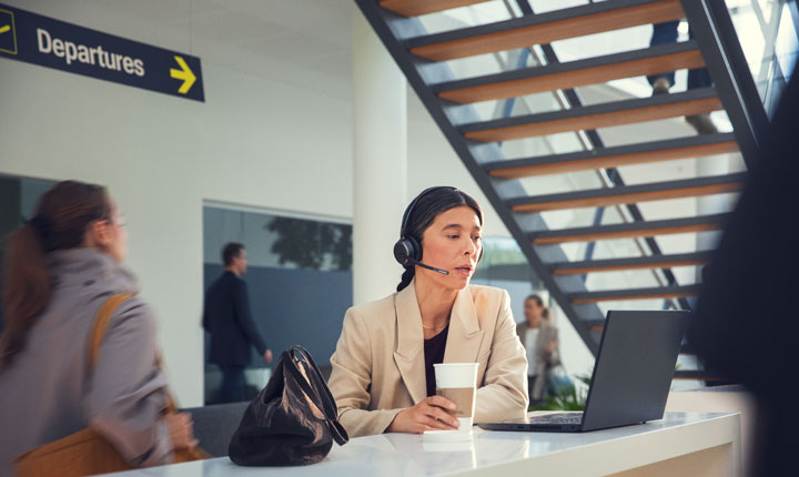 Frau benutzt Headset und Laptop am Flughafen