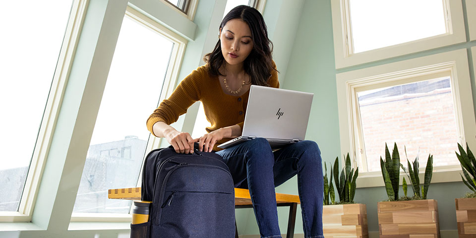 Woman packing her laptop into a backpack