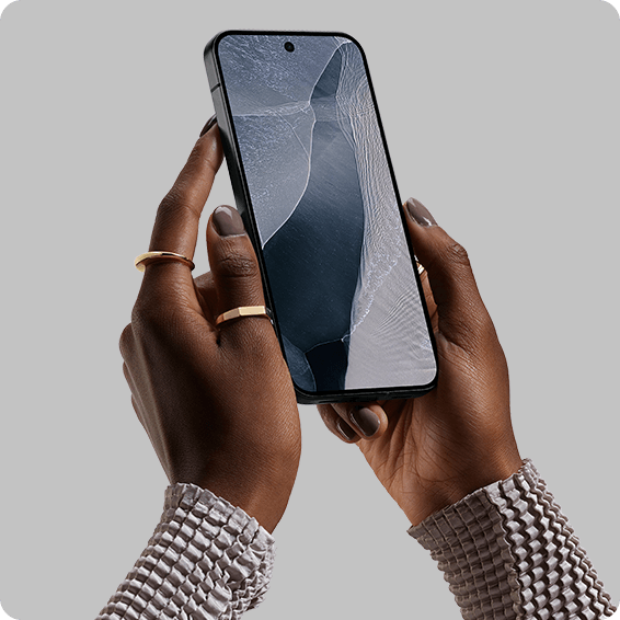 Hände halten Smartphone vor neutralem Hintergrund