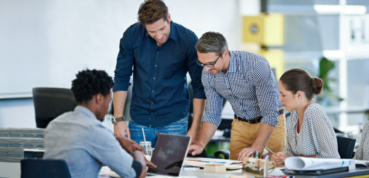 Vier Personen arbeiten in einem Büro an einem Projekt.