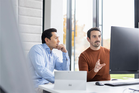 zwei Menschen sitzen vor einem computermonitor und analysieren Daten