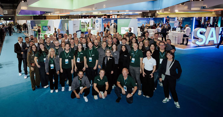 Große Gruppe von Fachleuten auf einer Messe, die Teamgeist und Branchenpräsenz in moderner Umgebung zeigt