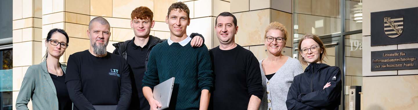Gruppe von sieben Personen vor einem Gebäude der Leitstelle für Informationstechnologie der sächsischen Justiz, Teamfoto im Arbeitsumfeld