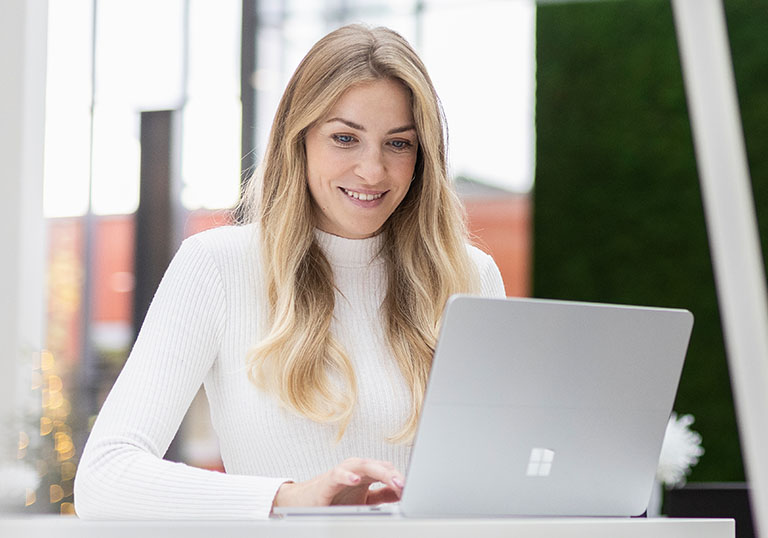 Woman working focused on laptop in modern, bright office with friendly atmosphere