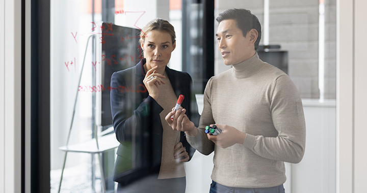 Man and woman discussing strategy on a board