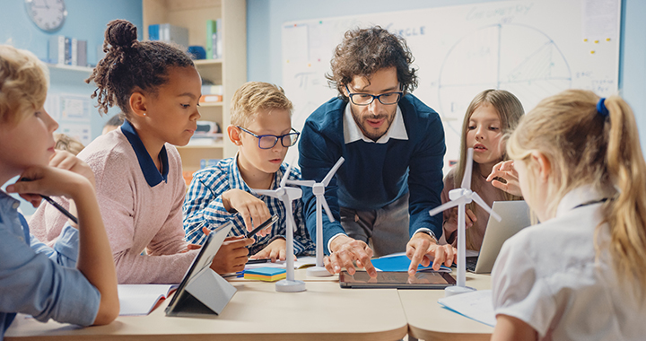 Eine Klasse von Kindern mit Tablets und einer Lehrerin, die ihnen hilft.