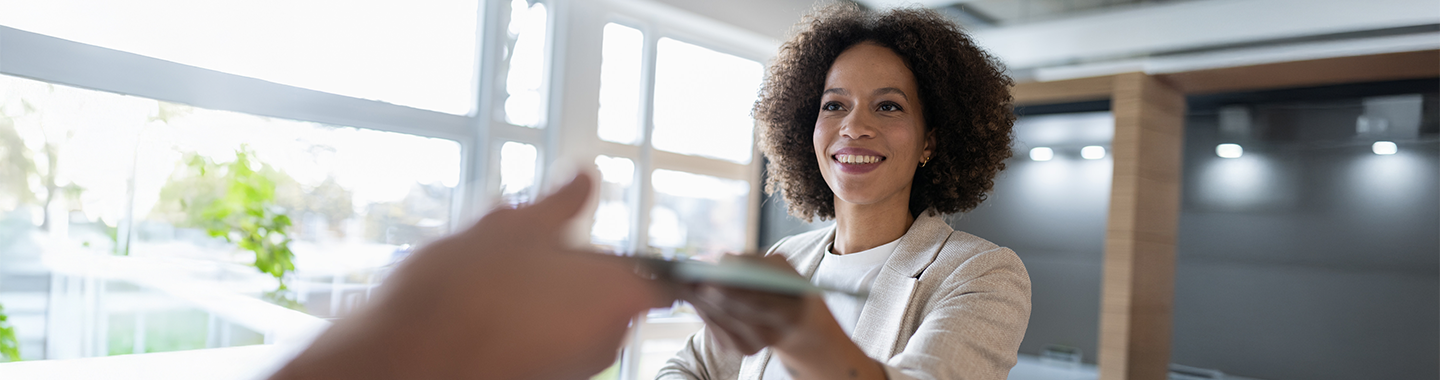 Happy woman is passing her tablet to a colleague