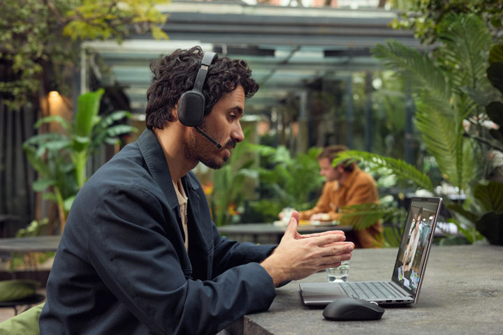 Man working on a laptop with headphones on, sitting outside