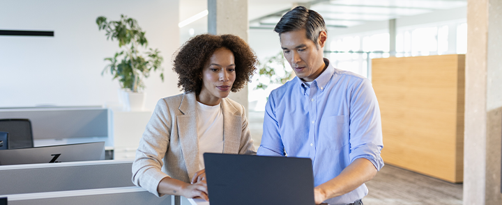 Two people working in an office together on a laptop