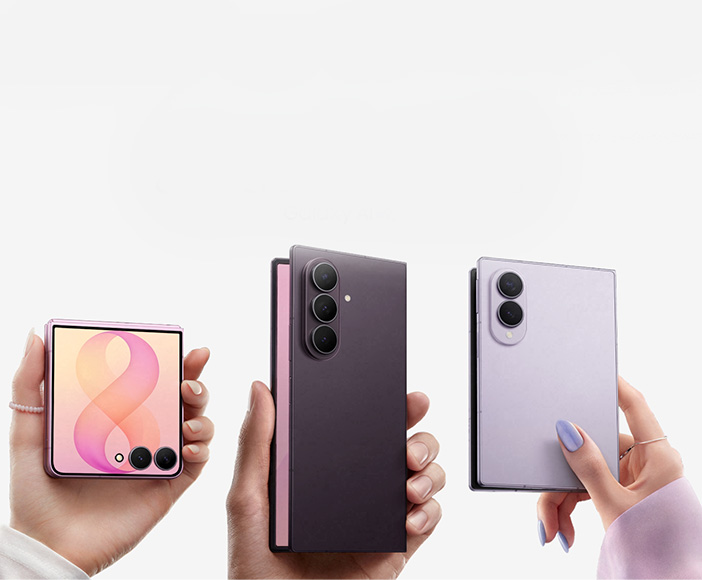 Three hands holding different models of foldable Samsung smartphones in various colors and open positions