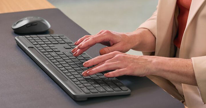 Frau die am Schreibtisch sitzt und mit einer Logitech Tastatur schreibt