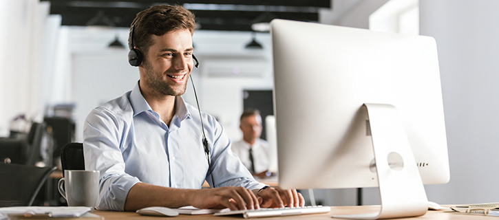 A man in a business suit is working on a laptop in an office