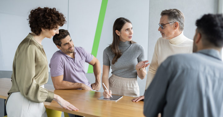 Five people standing in the office talking