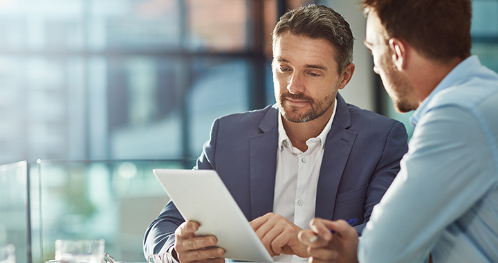 Zwei Männer überprüfen Daten auf einem Tablet.
