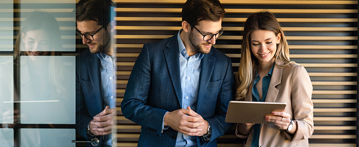 Ein Mann und eine Frau unterhalten sich, während sie auf ein Tablet schauen.