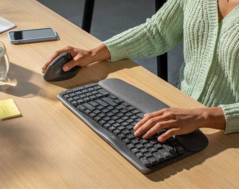 Person using ergonomic keyboard and mouse in bright workspace for comfortable computer operation
