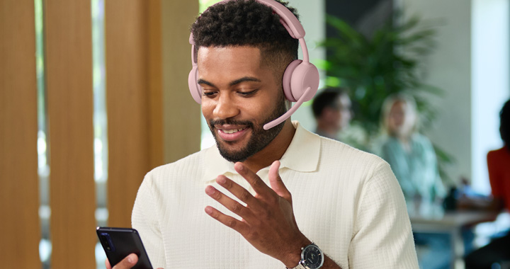 Mann mit einem rosafarbenen Headset und Handy in der Hand