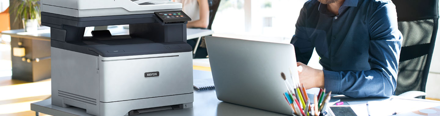 Xerox printer on table next to working employee