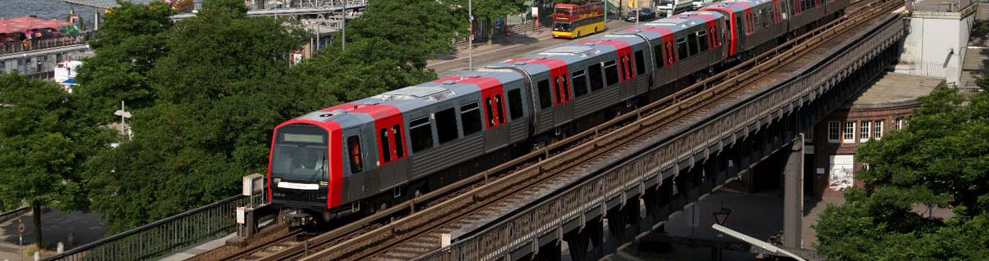Ein rot grauer Zug der über eine Brücke fährt