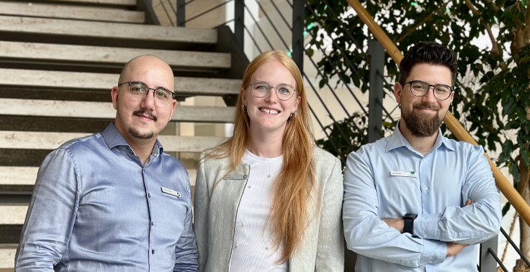 Drei Mitarbeitende vor Treppe im Bürogebäude