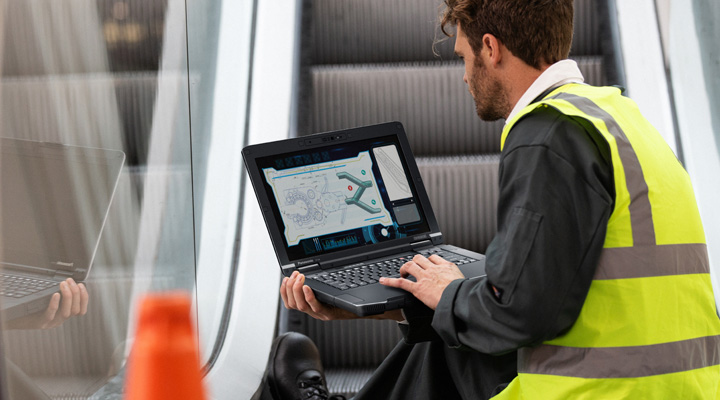 Ein Servicetechniker arbeitet mit einem Panasonic Thoughbook vor einer Rolltreppe