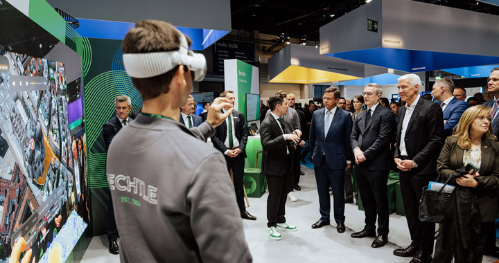 Person mit VR-Brille demonstriert digitale Technologie vor einer Gruppe von Fachbesuchern auf Messe